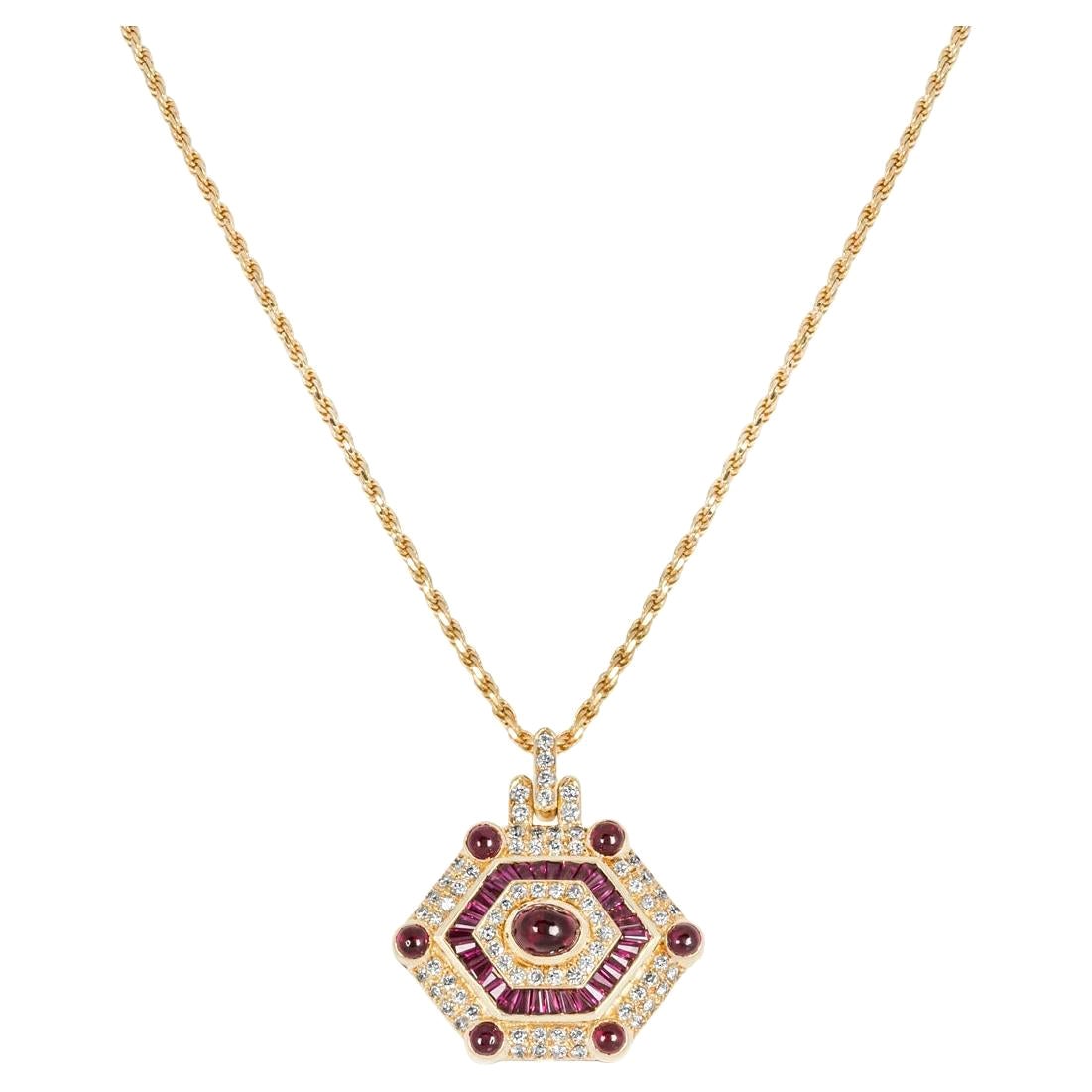A beautiful 18k yellow gold ruby and diamond pendant. The necklace consists of a diamond set bail with a bezel set ruby at the centre leading to a shield-shaped pendant. The pendant alternates between round brilliant cut diamonds, tapered baguette