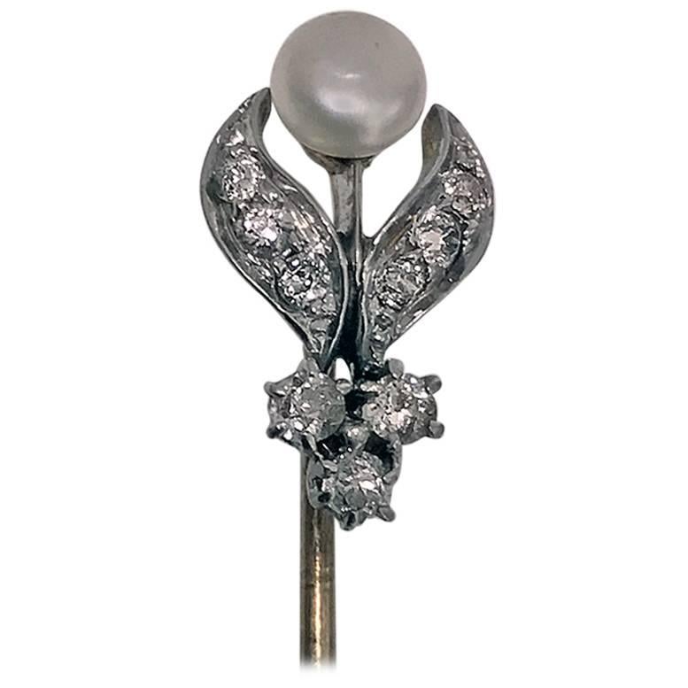 Platinum, 18K Diamond and natural Pearl Stickpin, C.1910. The stickpin in the form of an open foliate bud, set with a small silver grey button natural pearl, gauging approximately 4.8 mm, the foliate surround set with 9 small old mine cut diamonds,
