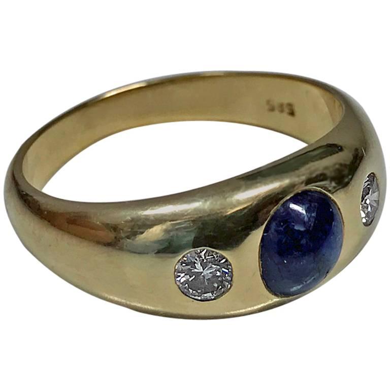 14K Cabochon Sapphire and Diamond Ring, C.1940. The ring centering a cabochon blue sapphire, gauging approximately 6.5 x 5.0 x 3.5 mm, with early round cut diamond on either side, approximately 0.30 ct, total diamond weight, average VS2 clarity,