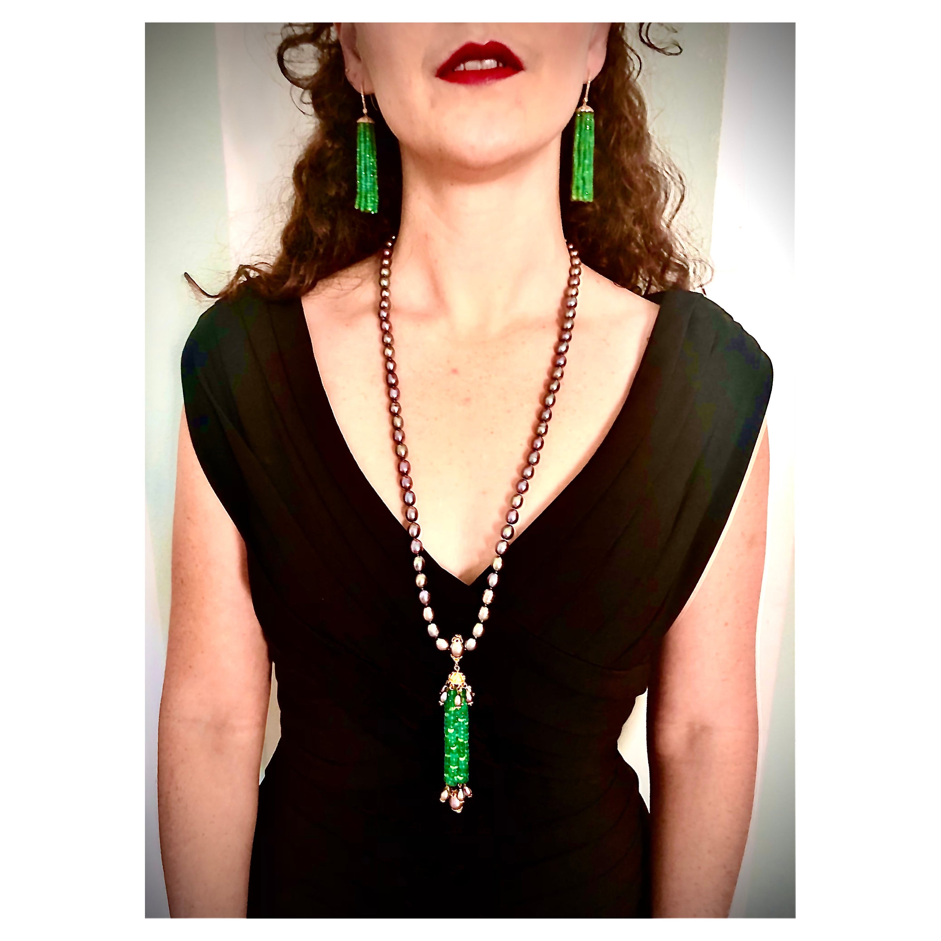 An elegant sautoir necklace consisting of a 24” rope of black freshwater oval pearls with an exquisite long tassel of well colored faceted emerald beads interspersed with faceted rock crystal beads. The tassel is gathered into an 18kt gold Mughal