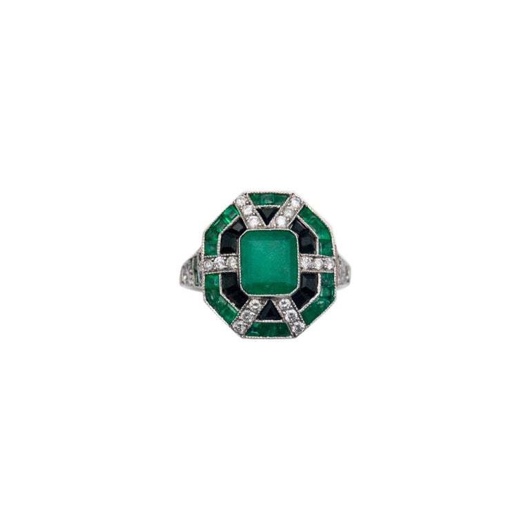 Extravagant Art Deco ring set with emeralds, onyxes and diamonds.
The geometric form of an octagon, characteristic of the Art Deco style.
Ring made of 0.950 platinum
Impressive central facet-cut natural emerald weighing 2 ct, surrounded by radiating