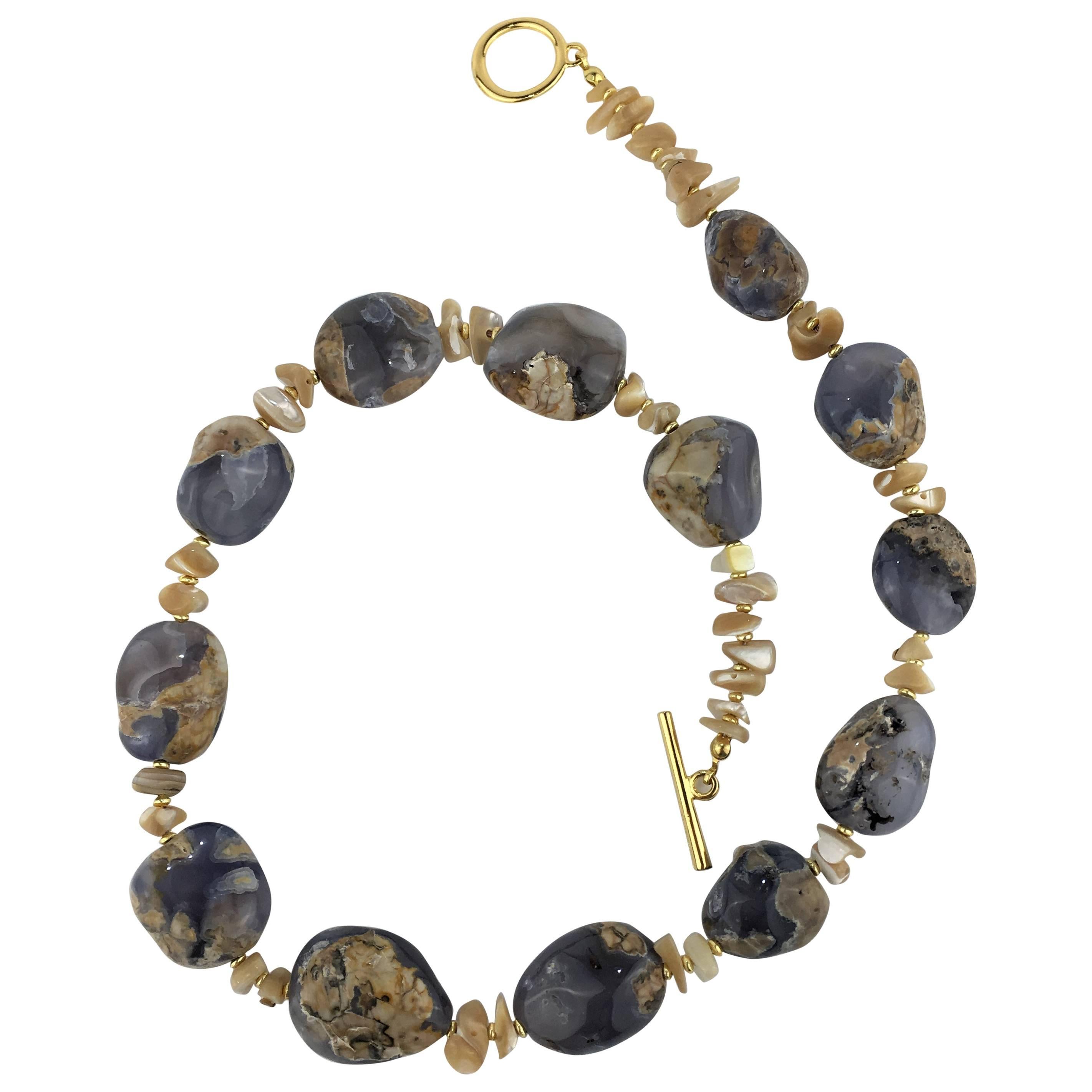 Necklace of large flat nuggets of polished blue Chalcedony in matrix.  The Chalcedony is enhanced with Polished Mother of Pearl chips and gold tone spacers.  The Chalcedony averages 25x22mm in size.  The necklace features a gold tone toggle clasp