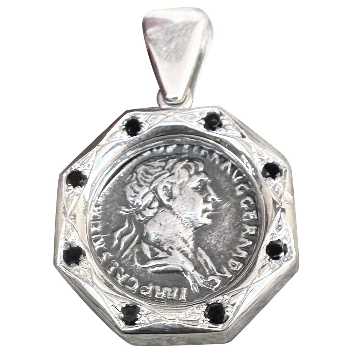 Dieser exquisite Silberanhänger zeigt eine echte römische Silberdenar-Münze aus dem 2. Jahrhundert n. Chr., die auf der Vorderseite Kaiser Trajan und auf der Rückseite den Gott Mars abbildet. Der Anhänger ist mit 8 schwarzen Diamanten 0,30 KT