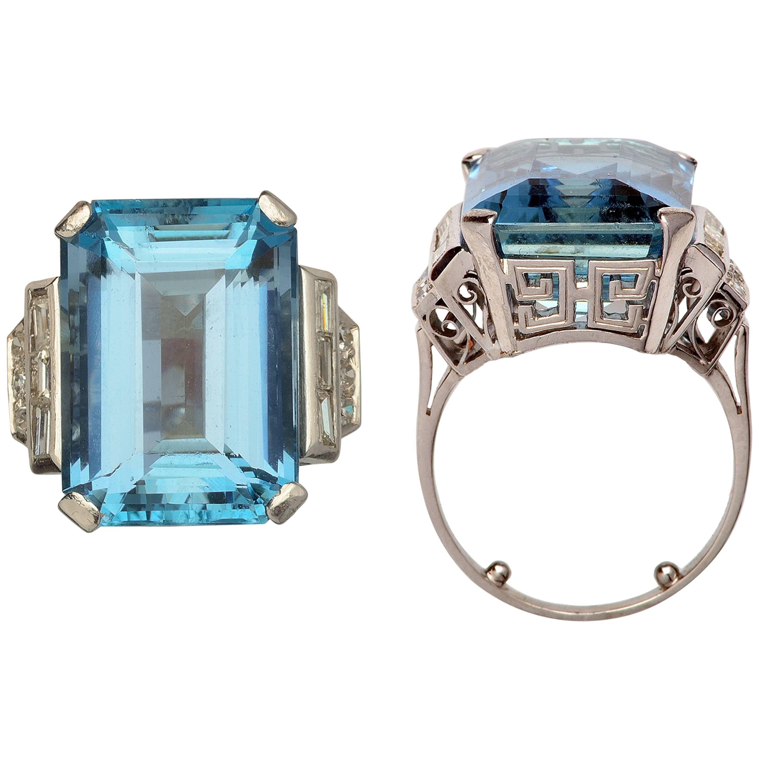 This cluster ring showcases a stunning 15´67 carats Aquamarine at its center. Displaying its stunning Santa María´s intense blue color and exceptional clarity. This elegant jewel is accentuated by baguette diamonds and brillant cut-diamonds