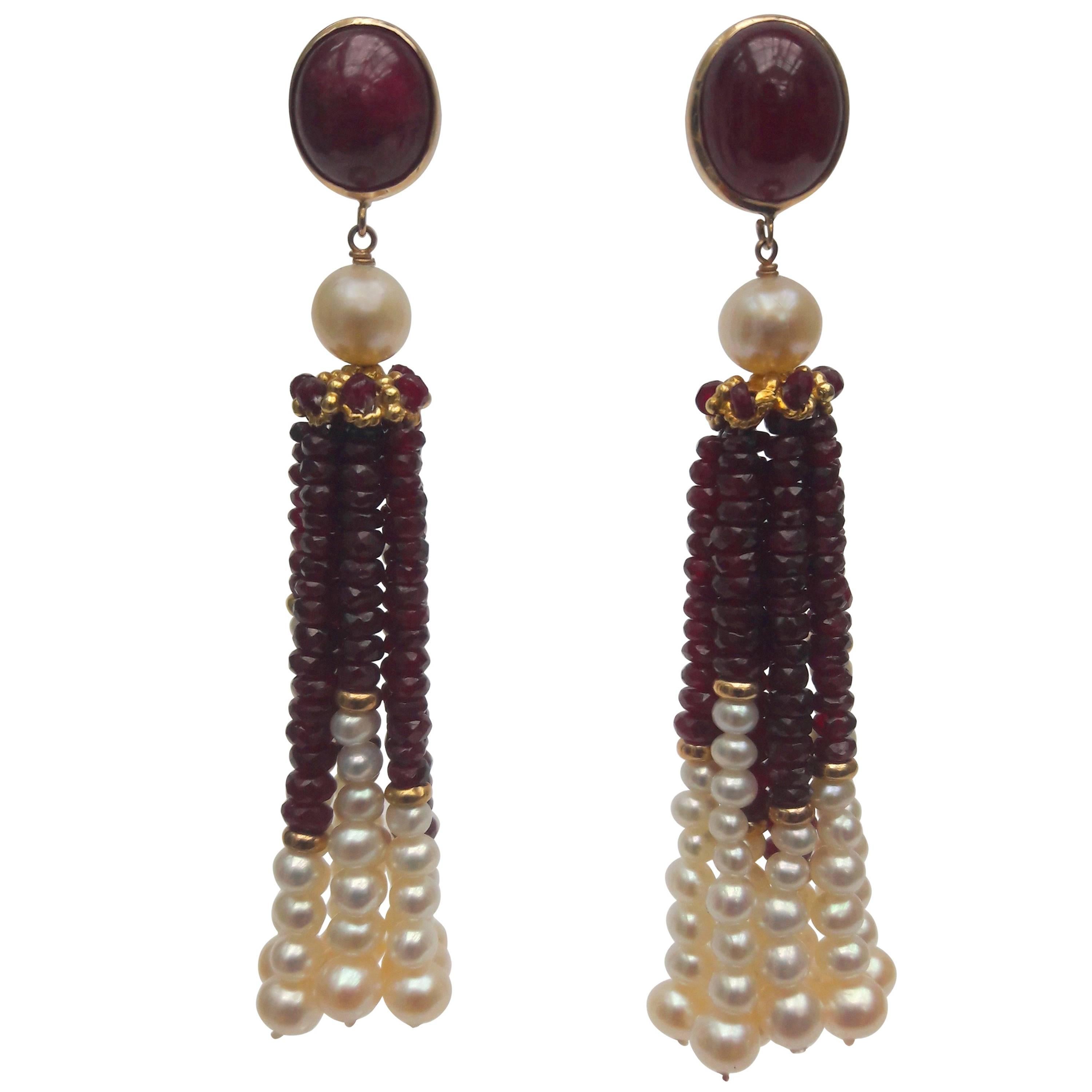 These tassel earrings are composed of faceted ruby beads and graduated white pearls (1.5 mm- 4 mm), divided by a 14 K yellow gold roundels. The tassels dangle from a filigree 14 k yellow gold cap, decorated with tiny faceted ruby beads. Atop the cap