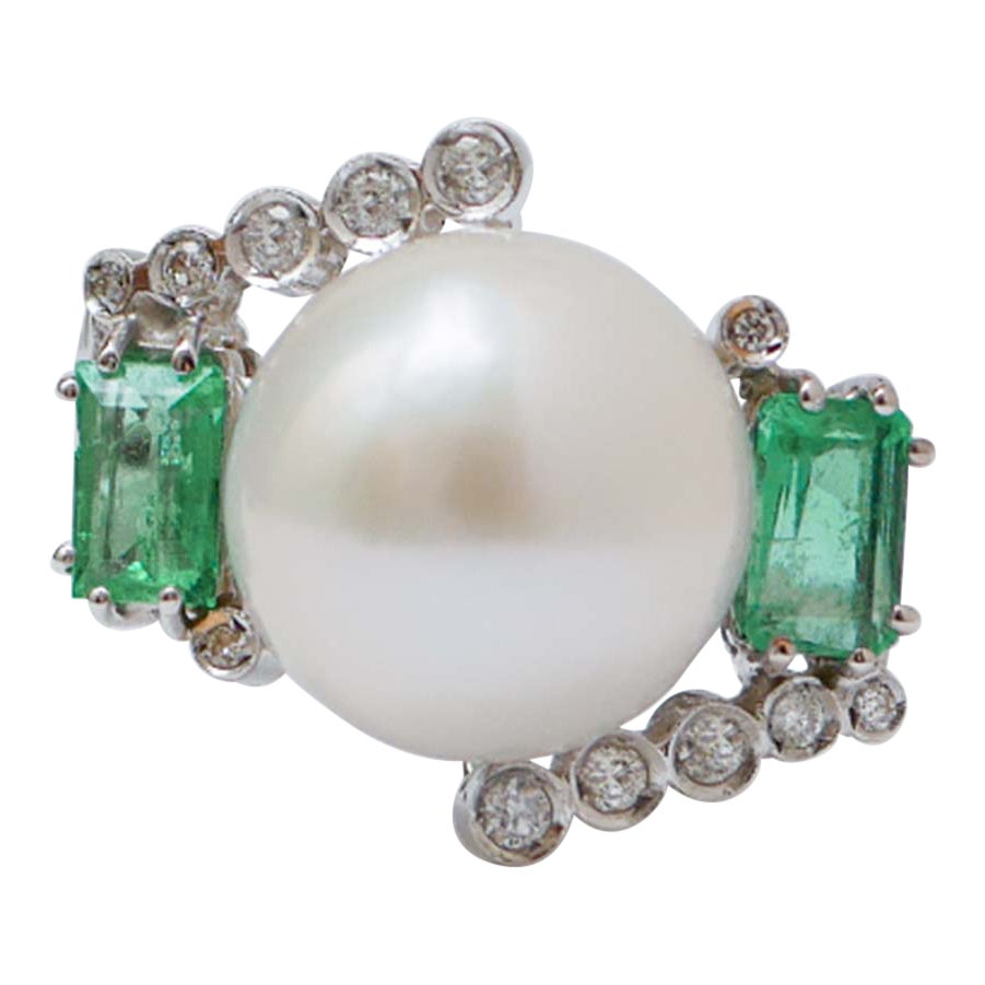 Anello in platino con perle bianche da 13 mm, smeraldi e diamanti.
