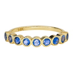 Anello mezza eternità in oro 14k con gemma blu.