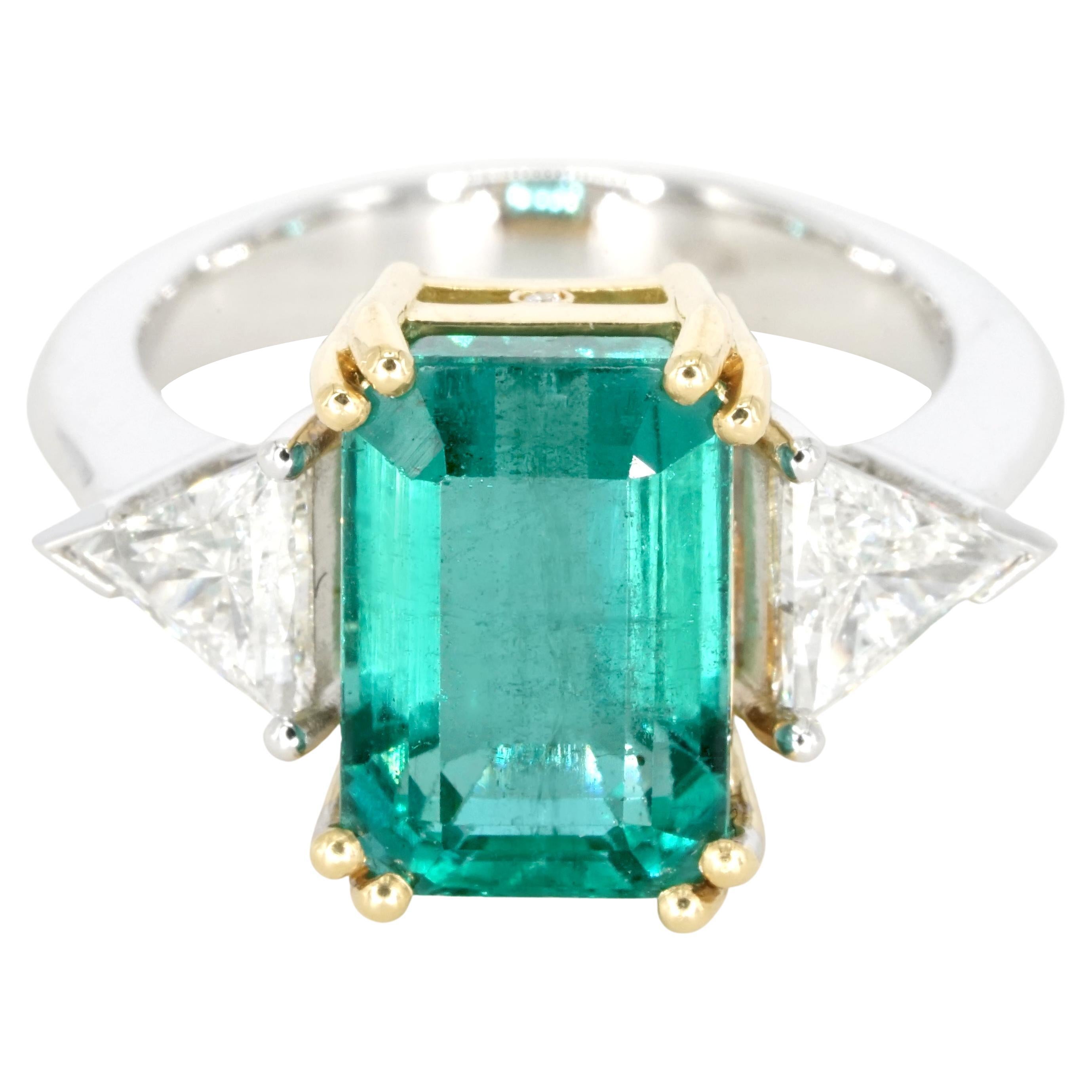 This exquisite emerald ring features an emerald-cut, natural green emerald, dual-certified by both IGI Antwerp and the prestigious Gemological Institute of America (GIA). The emerald's clarity is of an exceptional standard, a rarity in natural gems,