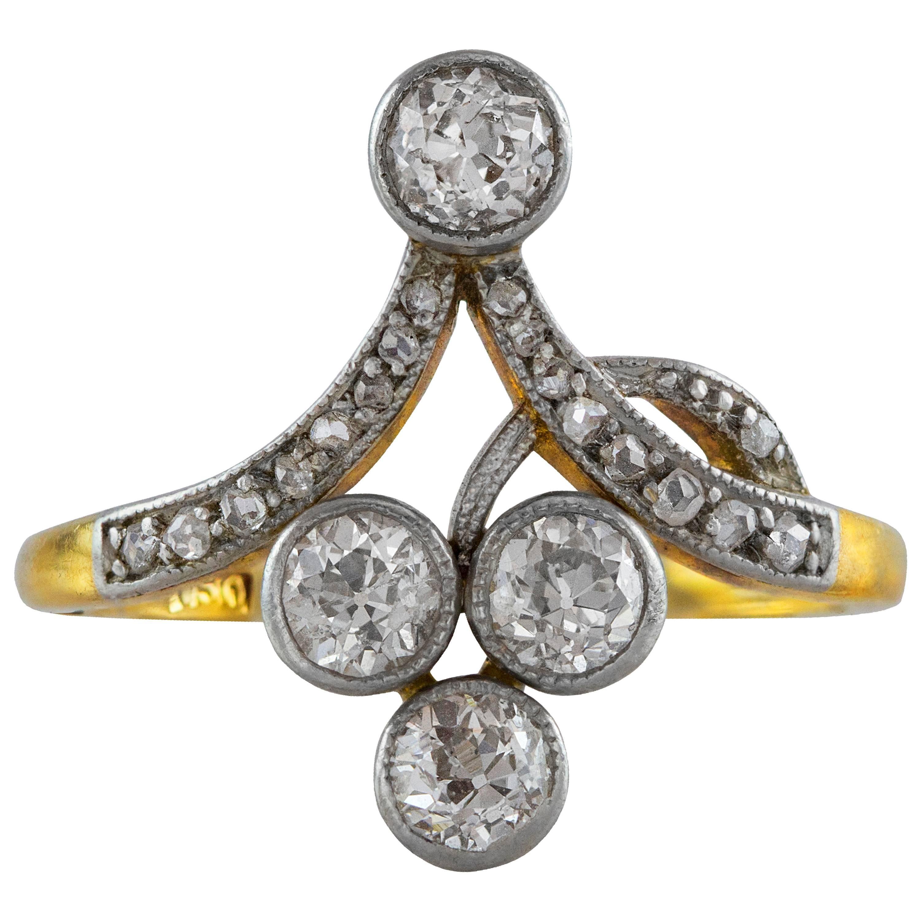 Este anillo antiguo presenta 4 diamantes de la Vieja Europa y diamantes talla única más pequeños en un intrincado diseño. El peso de los diamantes es de aproximadamente 0,78 quilates en total. Finamente fabricada en oro amarillo de 18 quilates.