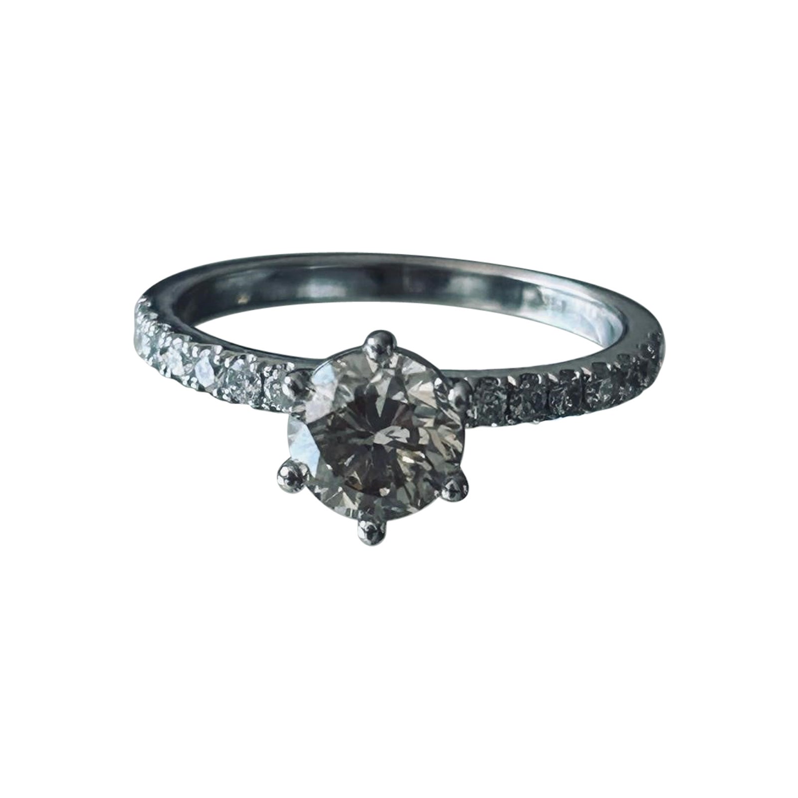 In der Mitte dieses exquisiten Rings befindet sich ein natürlicher, runder Diamant im Brillantschliff mit einem Gewicht von 1,03 Karat, der für außergewöhnliches Funkeln und zeitlose Eleganz sorgt. Das Band ist mit seitlichen Diamanten von insgesamt