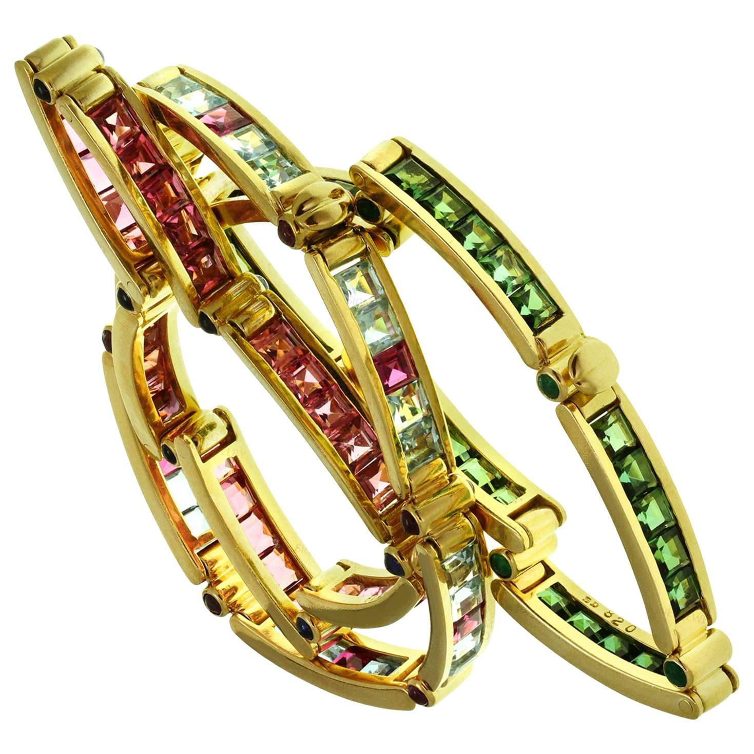 This rare and fabulous trio of Bulgari bracelets is crafted in 18k yellow gold and set with a colorful array of square-cut gemstones - pink and green tourmalines weigh an estimated 15.00 carats, aquamarines weigh an estimated 4.80 carats, and rubies