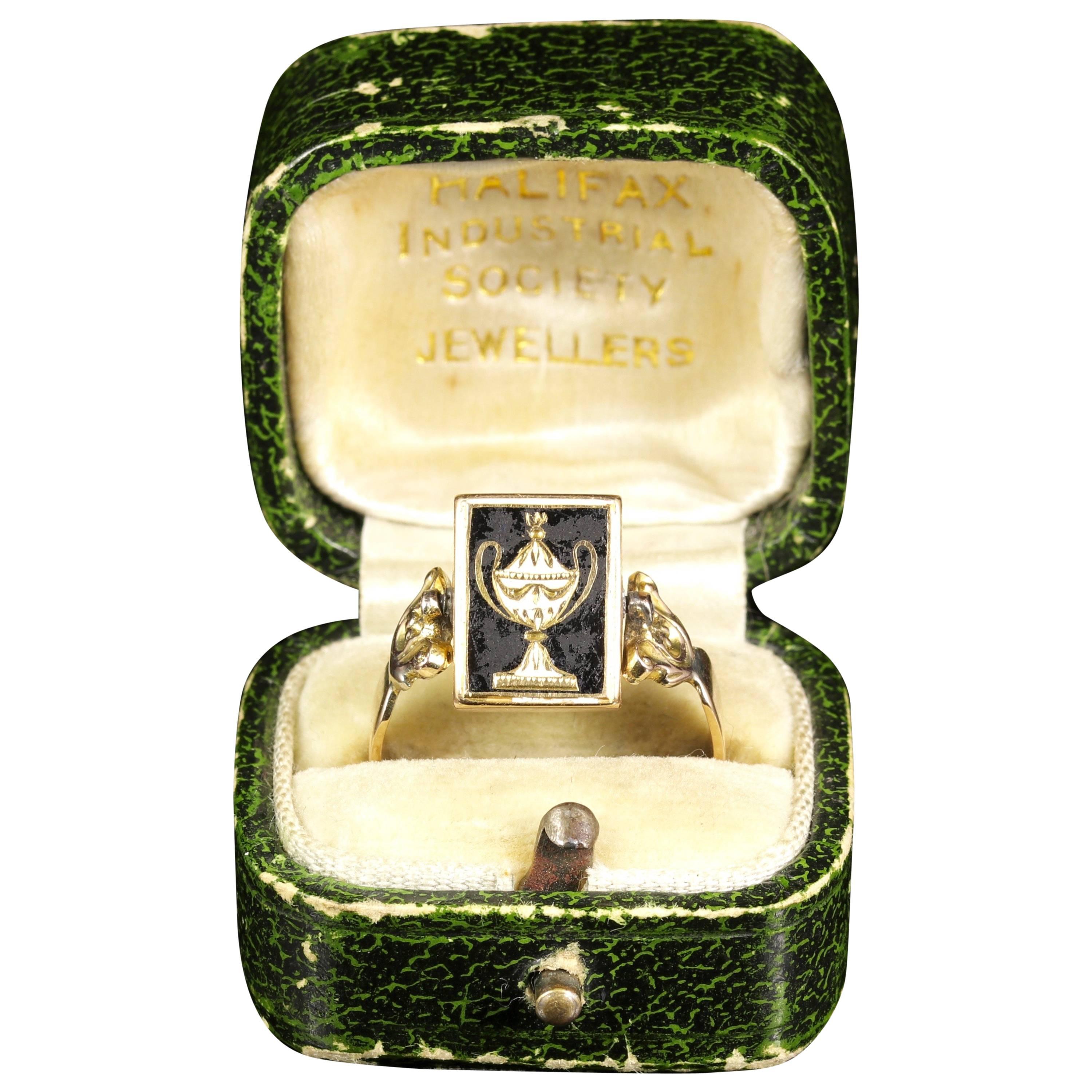 This is a genuine Georgian 18ct Yellow Gold mourning ring with original box.

On the front of the ring is a fabulous Enamel urn with intricate Gold details. 

The face of this stunning ring actually spins 360 degrees to reveal a hidden locket of