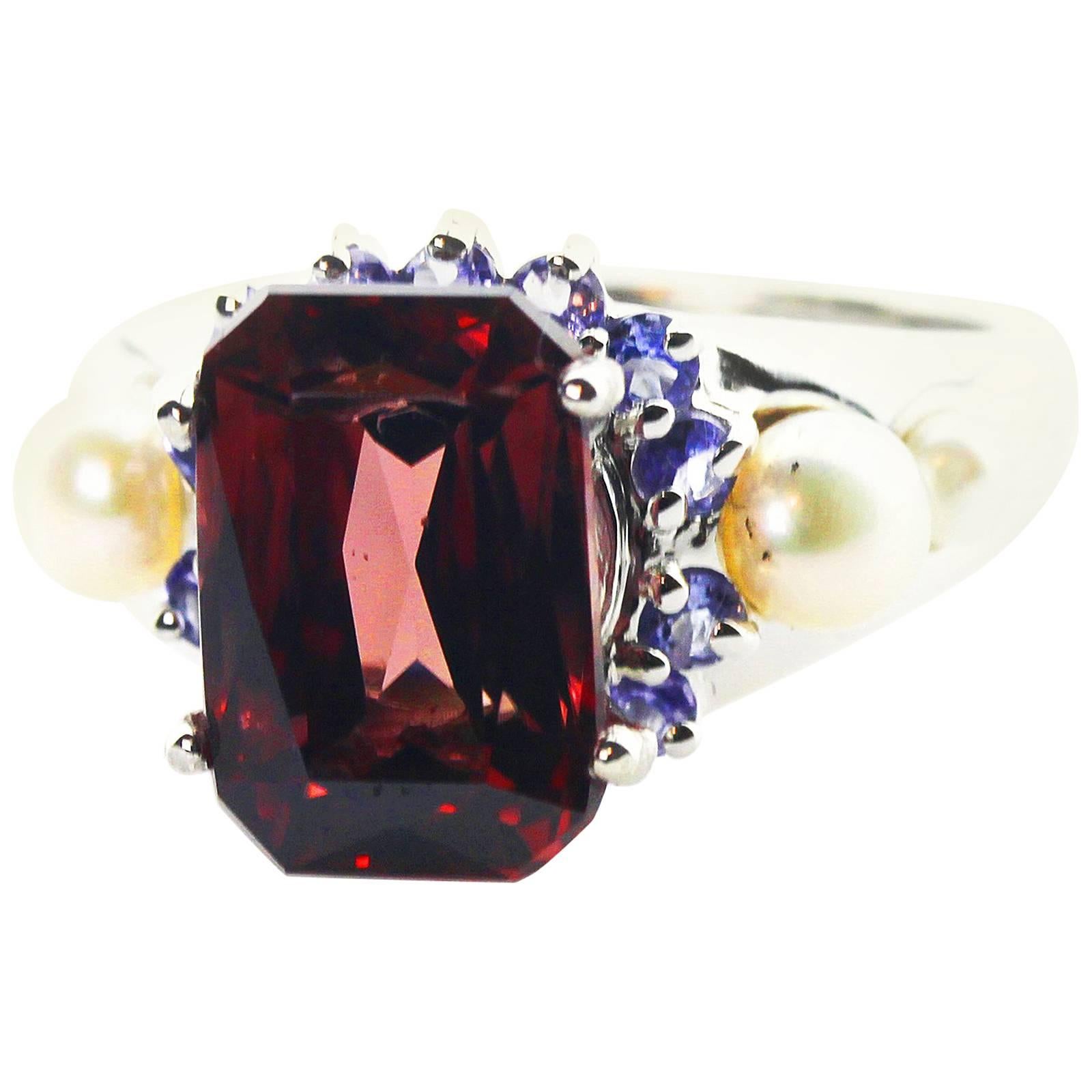 This 7.2 Carat glittering natural red Zircon measures 12 mm x 8 mm and is set in a Sterling Silver ring enhanced with blue Sapphires and white Pearls. The ring is size 7 (sizable).   There are no eye visible inclusions in this magnificent rare