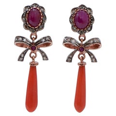 Orecchini con corallo, rubini, diamanti, oro rosa e argento.