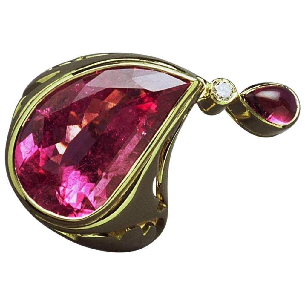 18ct yellow gold Paisley ring set with a 9.66ct fancy cut bright pink tourmaline, a diamond and smaller pear-shaped pink tourmaline cabochon are set in a drop linked to the tip of the ring. Paisley derived shapes are pierced down the sides of the