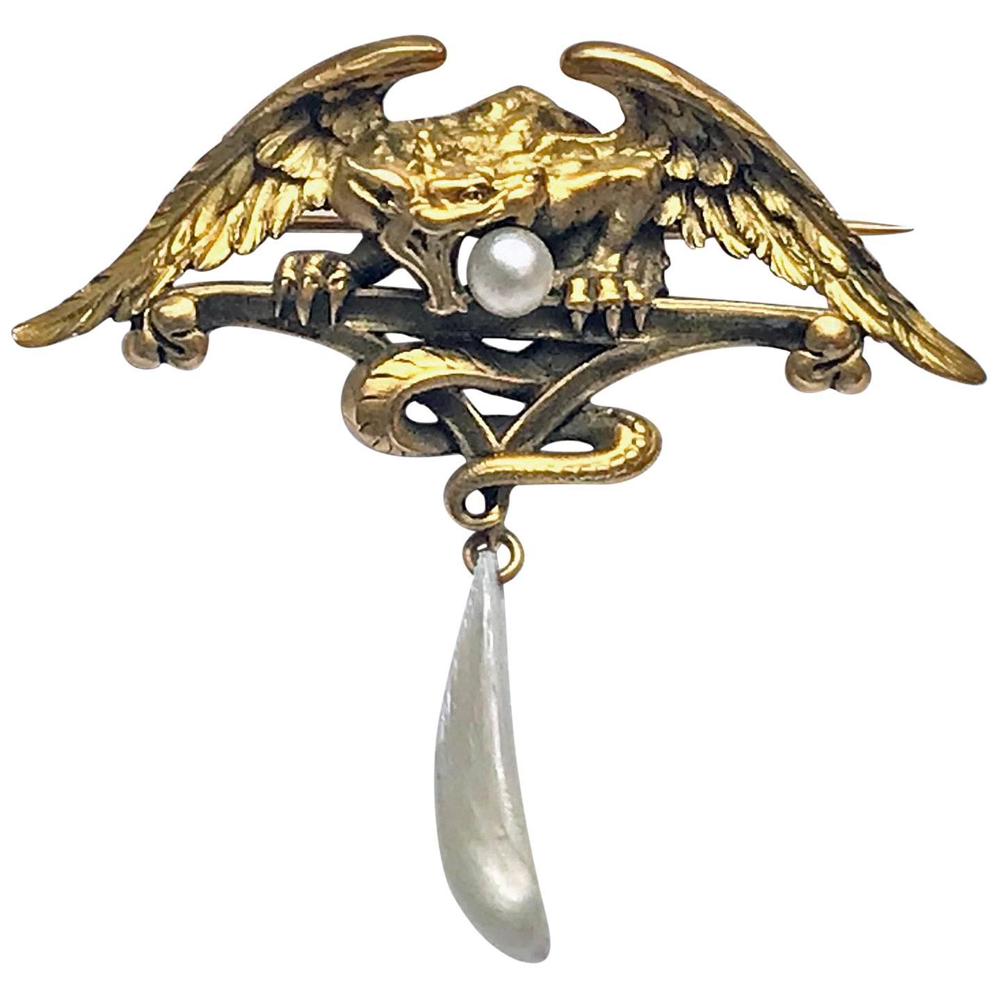 French Art Nouveau 18K mythological brooch Pendant, C.1900. The brooch pendant depicting a mythological combination including part eagle, part serpent griffin carrying a pearl in mouth and suspending a mother of pearl. Width (wing spread): 2.25