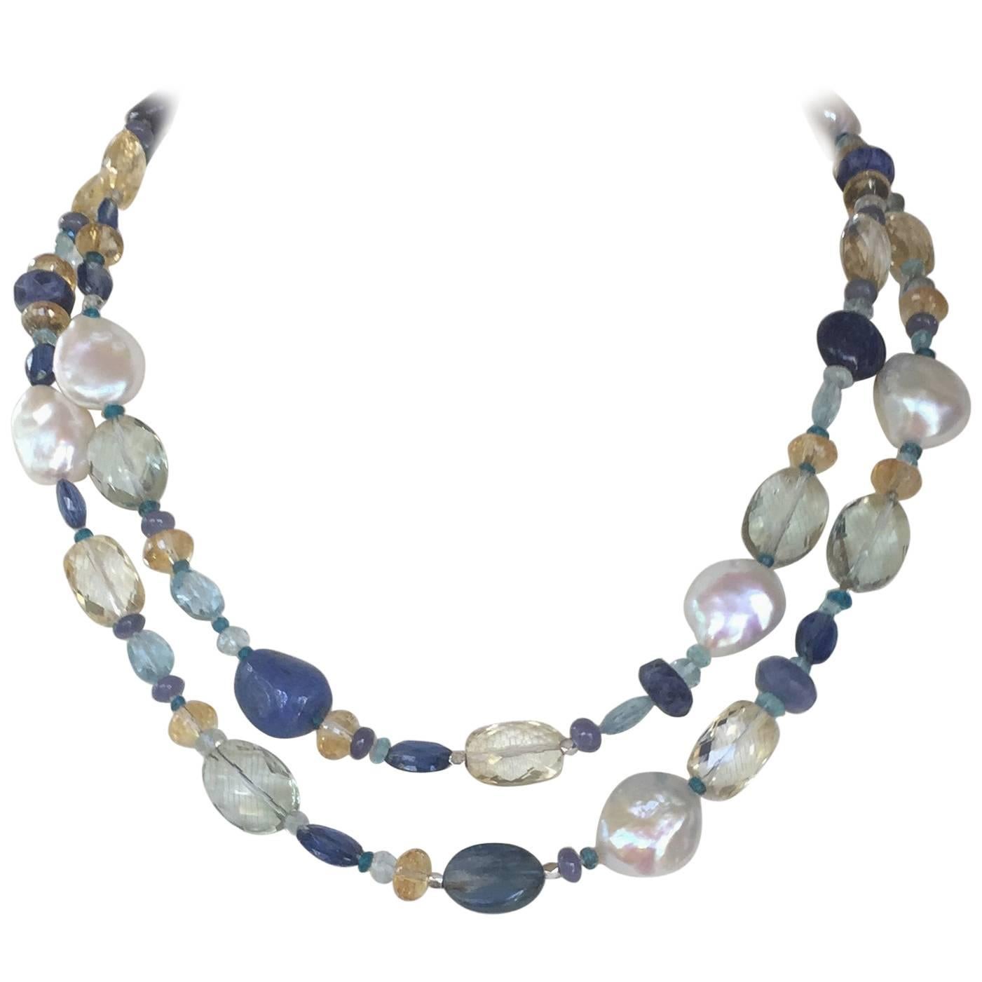 This pearl and semi-precious long necklace has a matching tassel and 14k white gold. The beautiful colors are composed of Kyanite, Iolite, Citrine, Tanzanite, Lapis Lazuli, Sapphire, Green Amethyst , Blue Agate, Aquamarine, Topaz, and Laboradite. 