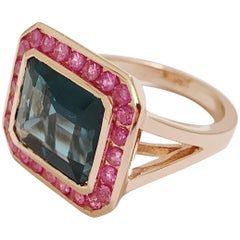 Ring aus Roségold mit dunkelblauem Topas und umgebendem rosa Saphir in Lünette