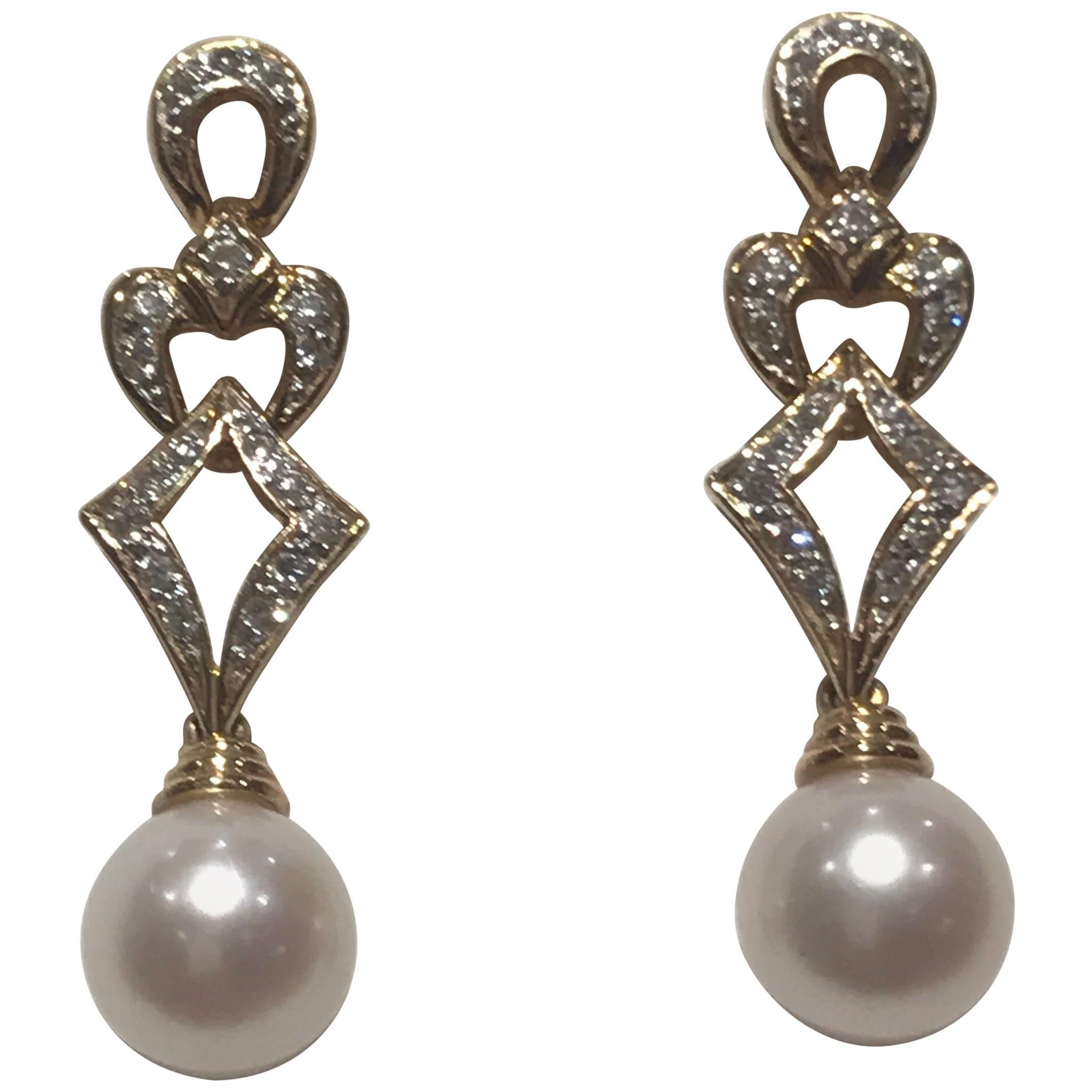 A pair of yellow gold and diamond earrings with a cultured pearl drop set in yellow gold, the earrings are hallmarked for 18k gold and have diamonds which are estimated to weigh about 0.3cts. The diamonds are bright and of good colour and clarity