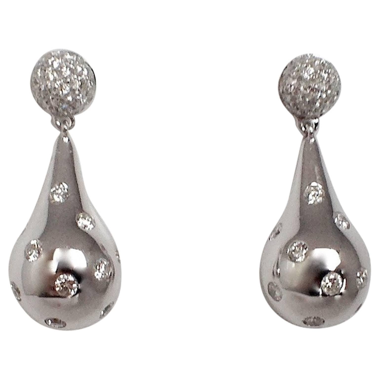 Orecchini a goccia in oro bianco 18 carati con diamante bianco Made in Italy 
Gli orecchini hanno un bottoncino tempestato di piccoli diamanti e sotto, che penzola, una goccia d'oro incastonata in modo irregolare con alcuni diamanti.
La caratura