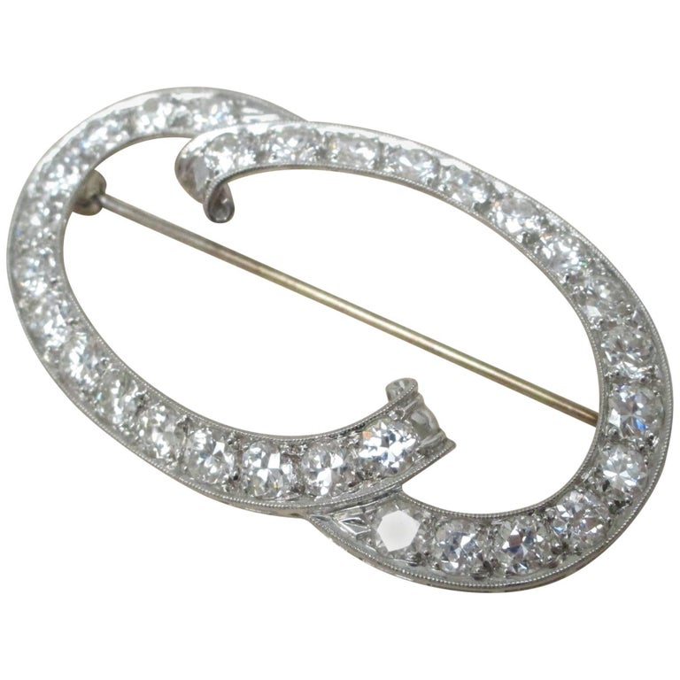 This stunning brooch is made from Platinum with 30 Diamonds chasing around it's graceful curves. The diamonds have a total weight of approximately 5.4 carats and are G color and VS2 clarity. The pin findings are made of 14K white gold. This pin eats