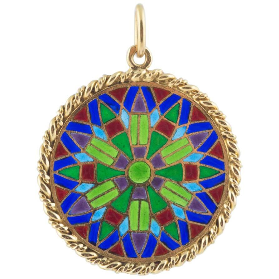 Recalling the stain glass windows of Notre Dame Cathedral in Paris, this 18k gold pendant is decorated with plique a jour (transparent) enamel of vibrant colors, separated by gold cloisons with a gold ropetwist border. Chain not included. 

French,