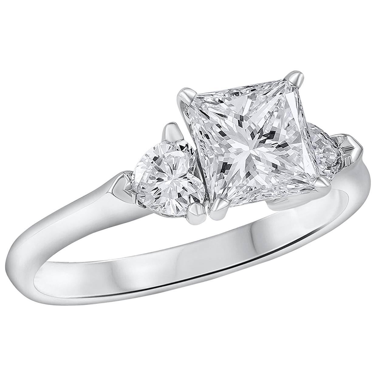 Showcases a 1.32 carats princess cut diamond flanked by a heart shape diamond on each side. The heart shape diamonds symbolize the two hearts that join together in the momentous event of an engagement. GIA certified the center stone as I color, VVS2