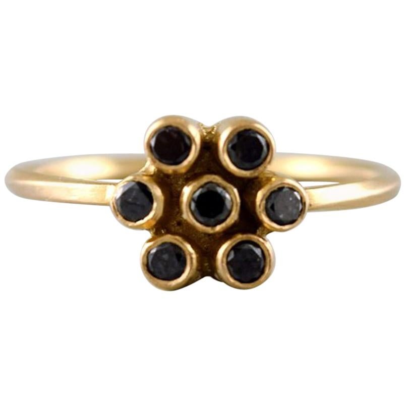 Carré ring in 18 kt. gold in the form of a flower. Adorned with 7 black diamonds