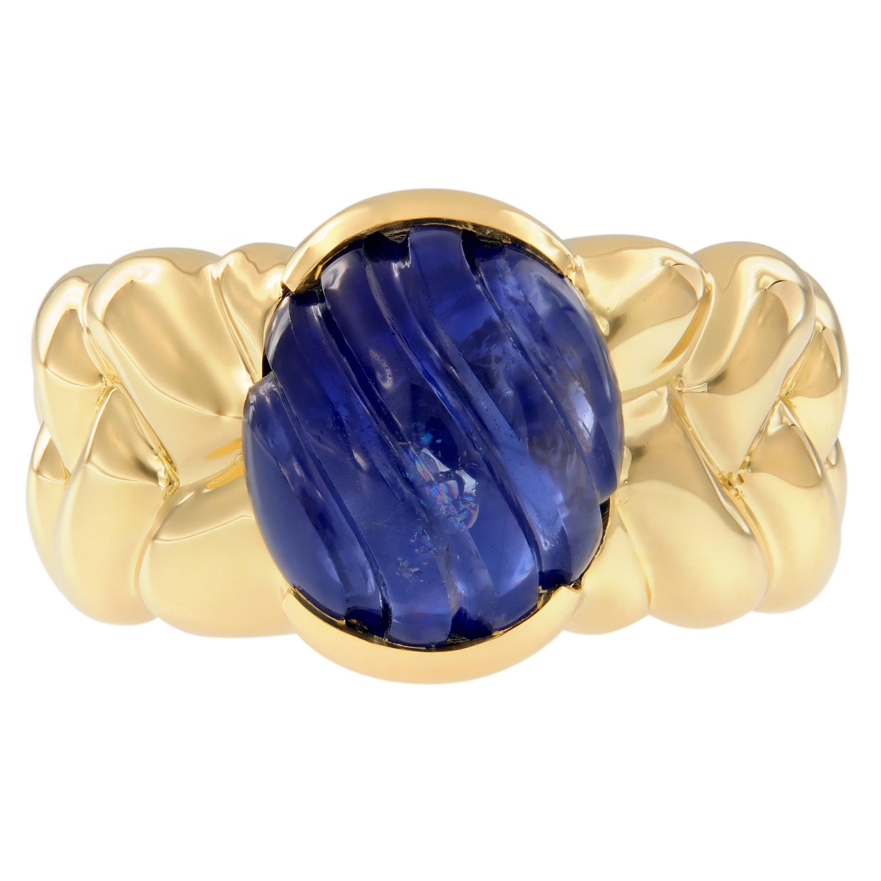 This modern ring features a bezel set blue sapphire center stone, accented with a braided band beautifully crafted in 18k yellow gold. Ring size is 6.25. Weighs 10.1 grams.

Blue Sapphire 6.67 ct