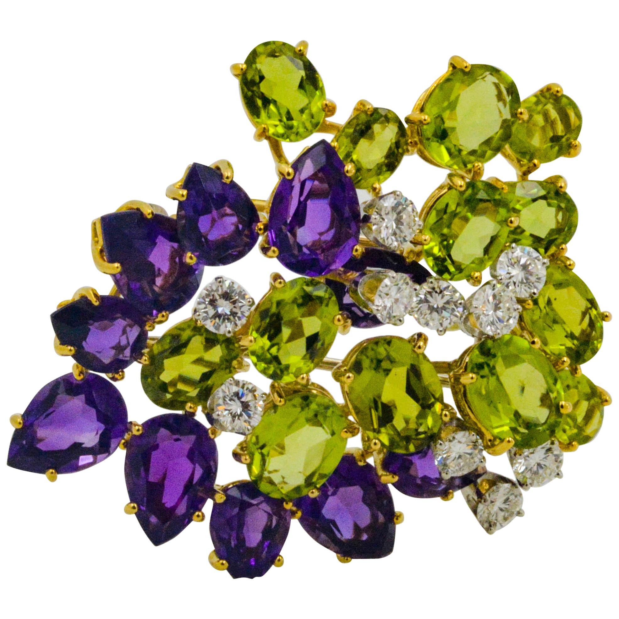 Crafted in 18K yellow gold, this free-form brooch has ten pear shaped amethyst 13.80ctw and 13 oval peridot 14.43ctw, accented with ten round brillant diamonds 2.00ctw (G color and VS clarity). This brooch showcases a luxe design with rich colors