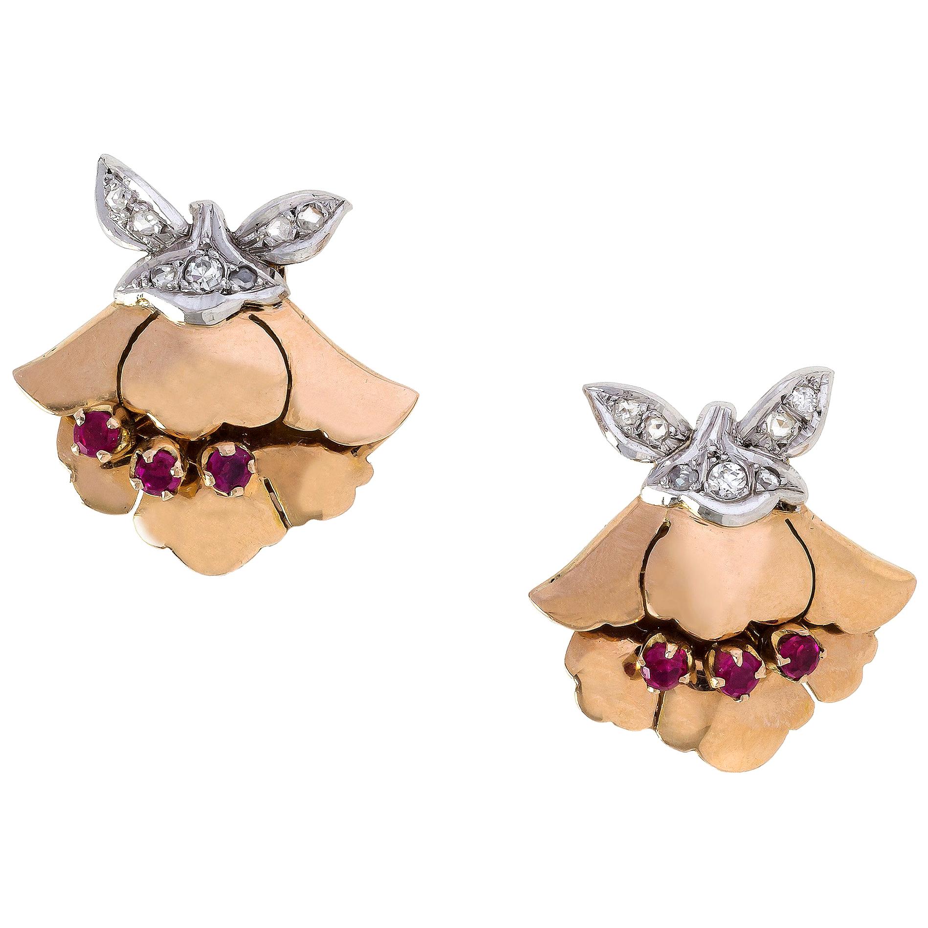 The 14 k gold earclips can also be worn as dressclips. They are designed as flowers with ruby set pistils and small leaves. The receptacles and leaves are made out of 14 k white gold and set with diamonds. The earclips are marked 585 and show