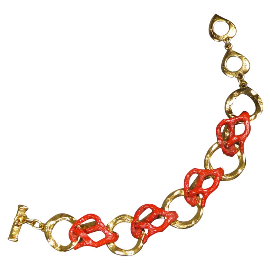 Circa 1980
France
Superbe bracelet en métal doré et corail de Robert Goossens pour Yves Saint Laurent datant des années 1980. Bracelet composé d'anneaux en métal doré martelé entrecoupés de maillons torsadés en métal émaillé rouge façon corail,