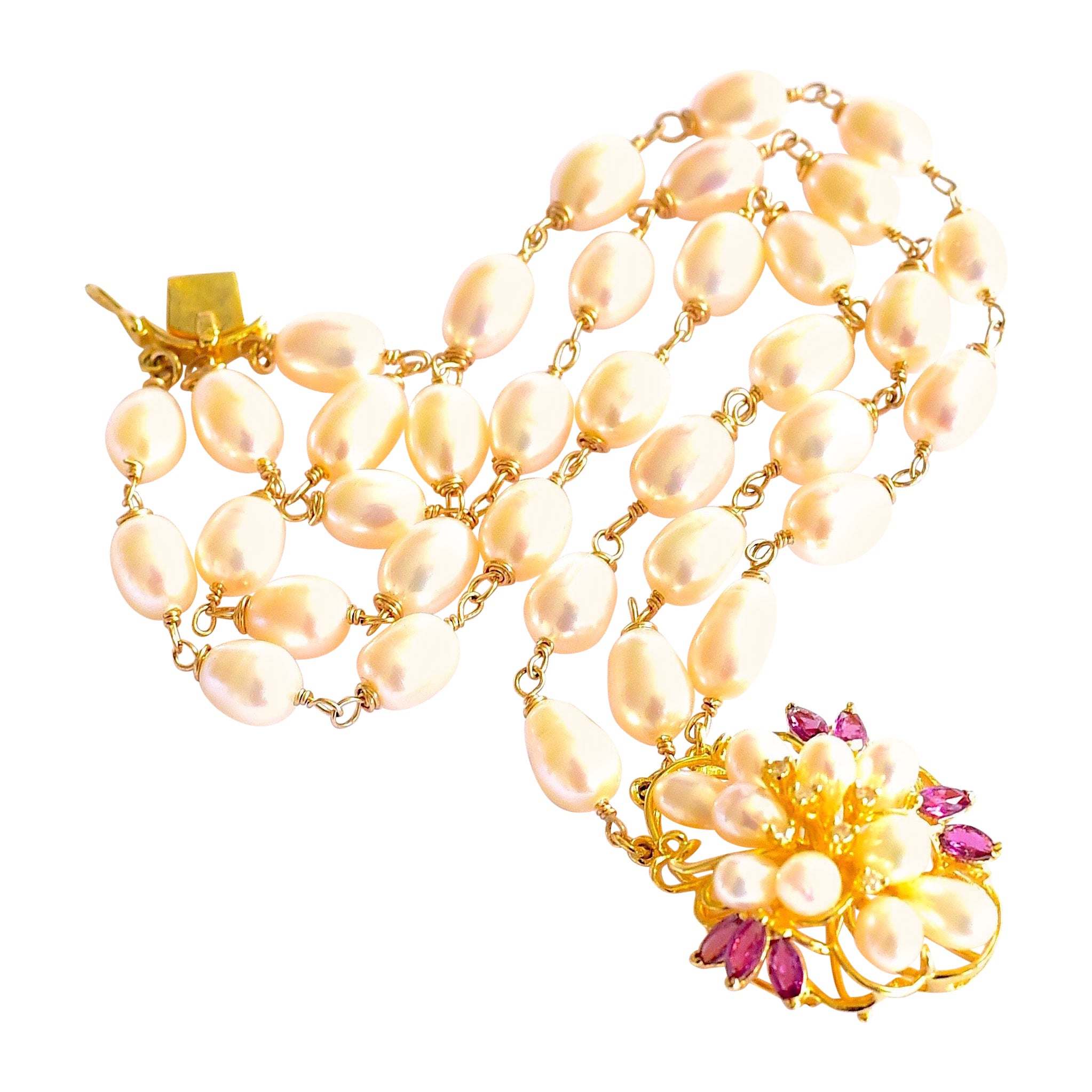 A stunning collection of rice shape freshwater pearls with amazing vintage style 14K yellow gold cluster clasp with pearl, diamond, ruby ornate floral. Not adjustable bracelet, but fits very well even larger hand. 
A wonderful bracelet for a lady! 