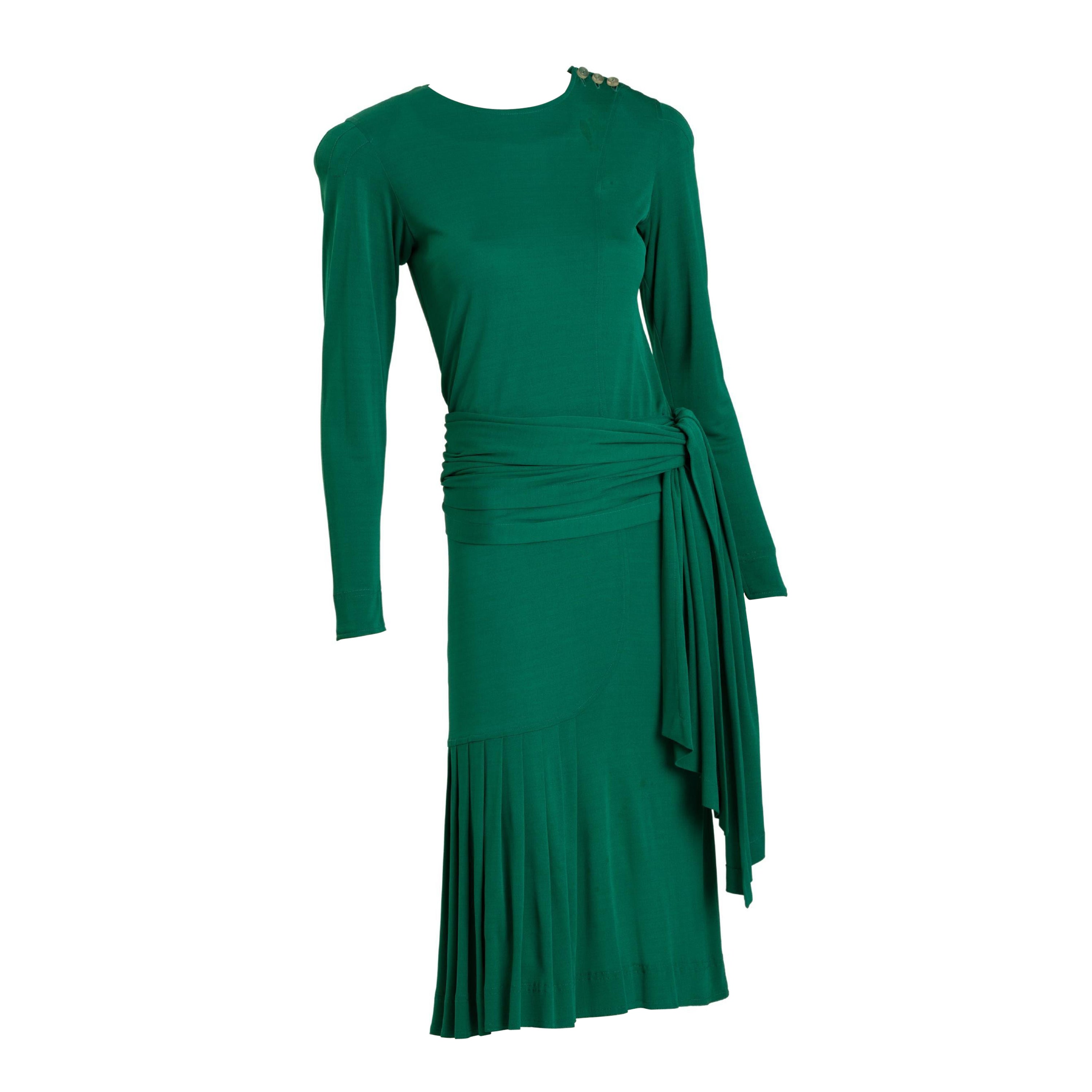 Jean Muir emerald green jersey cocktail dress with long wrap sash. Sash may also be worn as long scarf around neck, and tied at lower back. Front of dress has asymmetrical pleating. Three clear button closure at left collarbone, one on each cuff.