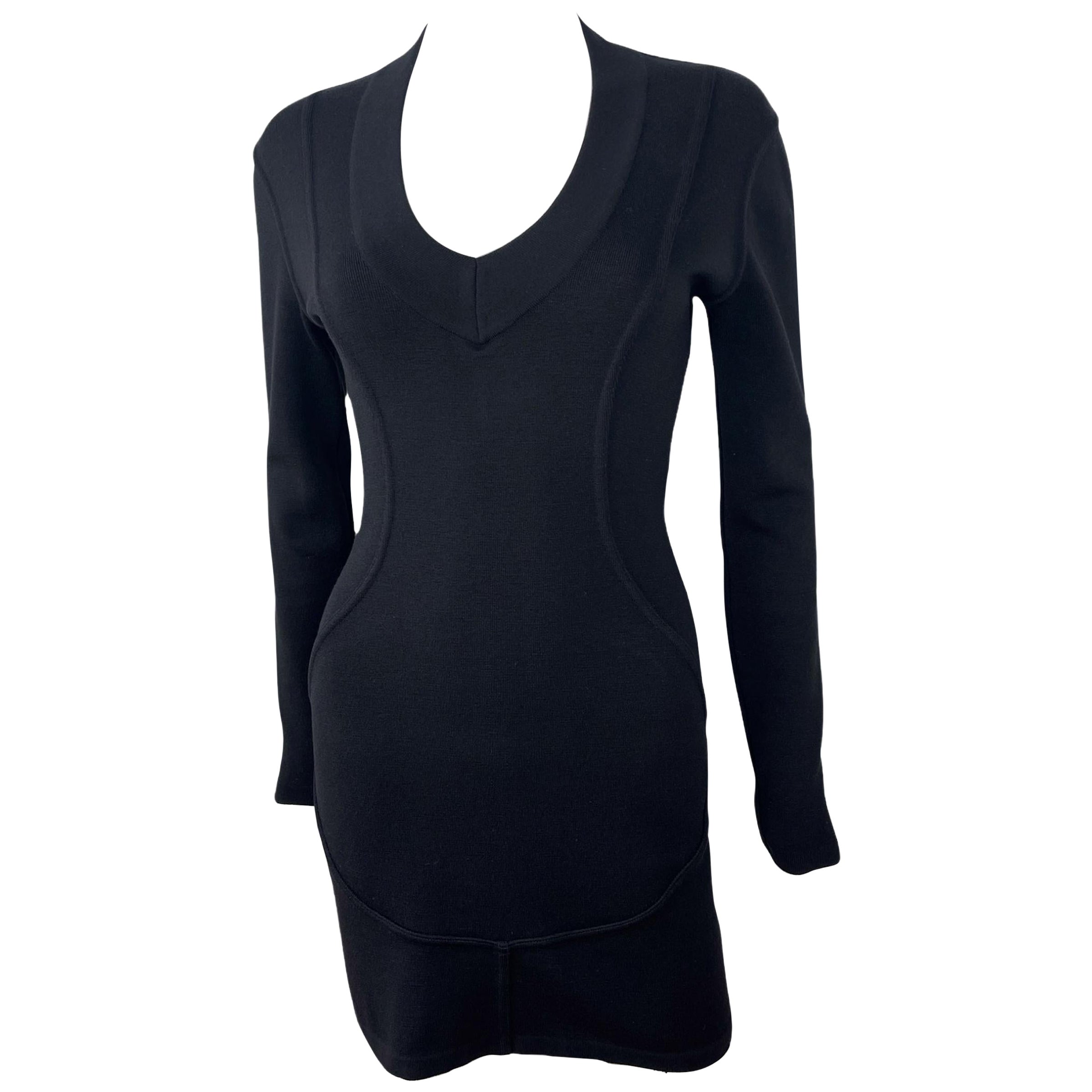 ALAÏA, Made in Italy, FW1990.
Bodycon black mini dress designed by Azzedine Alaïa for Fall-Winter 1990.
Deep V neck, long sleeves, short length.
86% wool - 10% nylon - 4% elastane

Good condition - small defect at the end of the collar, shown in