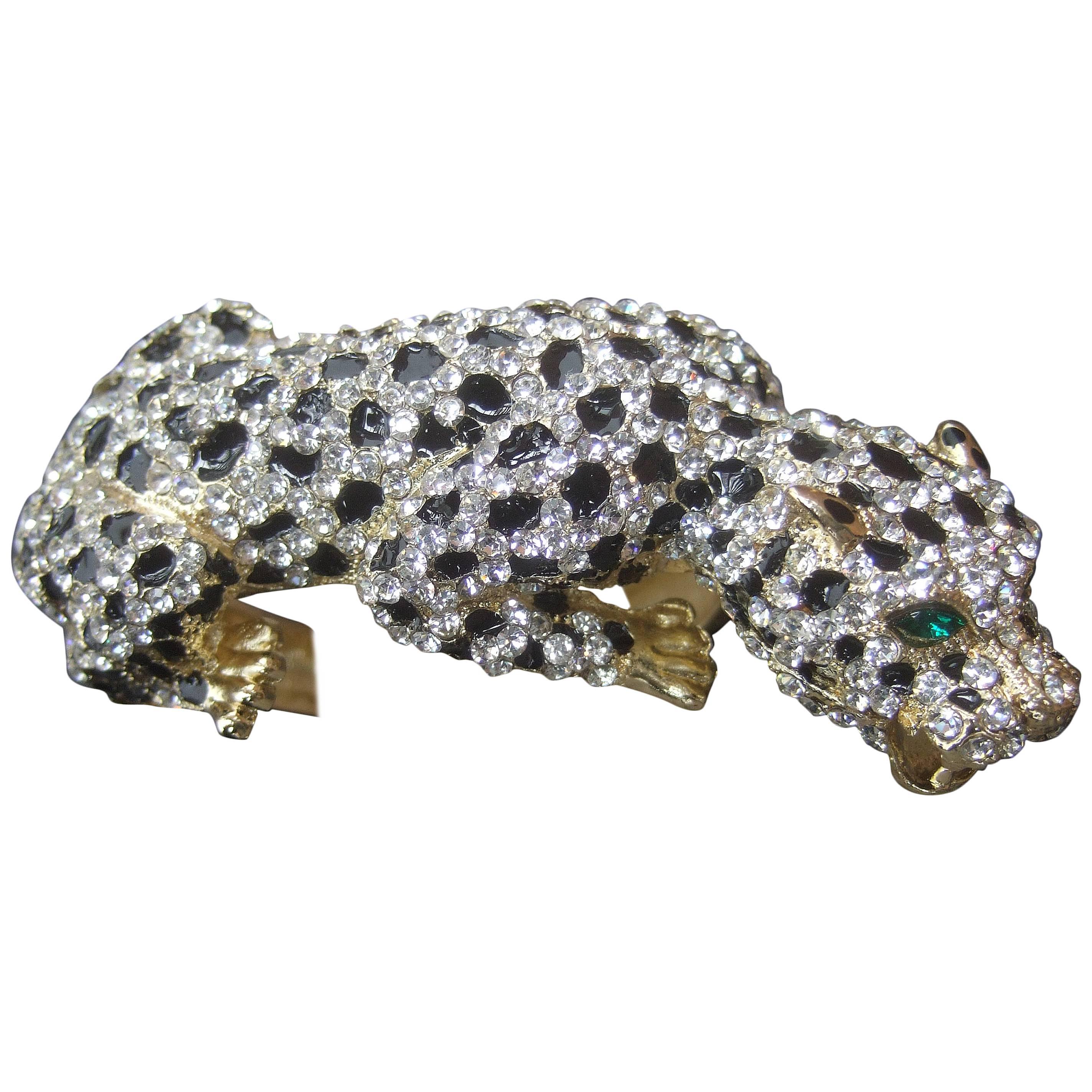 Sleek crystal encrusted enamel panther bracelet 
The hinged bracelet is designed with an exotic
jeweled panther

The felines body is embellished with glittering
diamante crystals and black enamel spots
The eyes are embedded with emerald