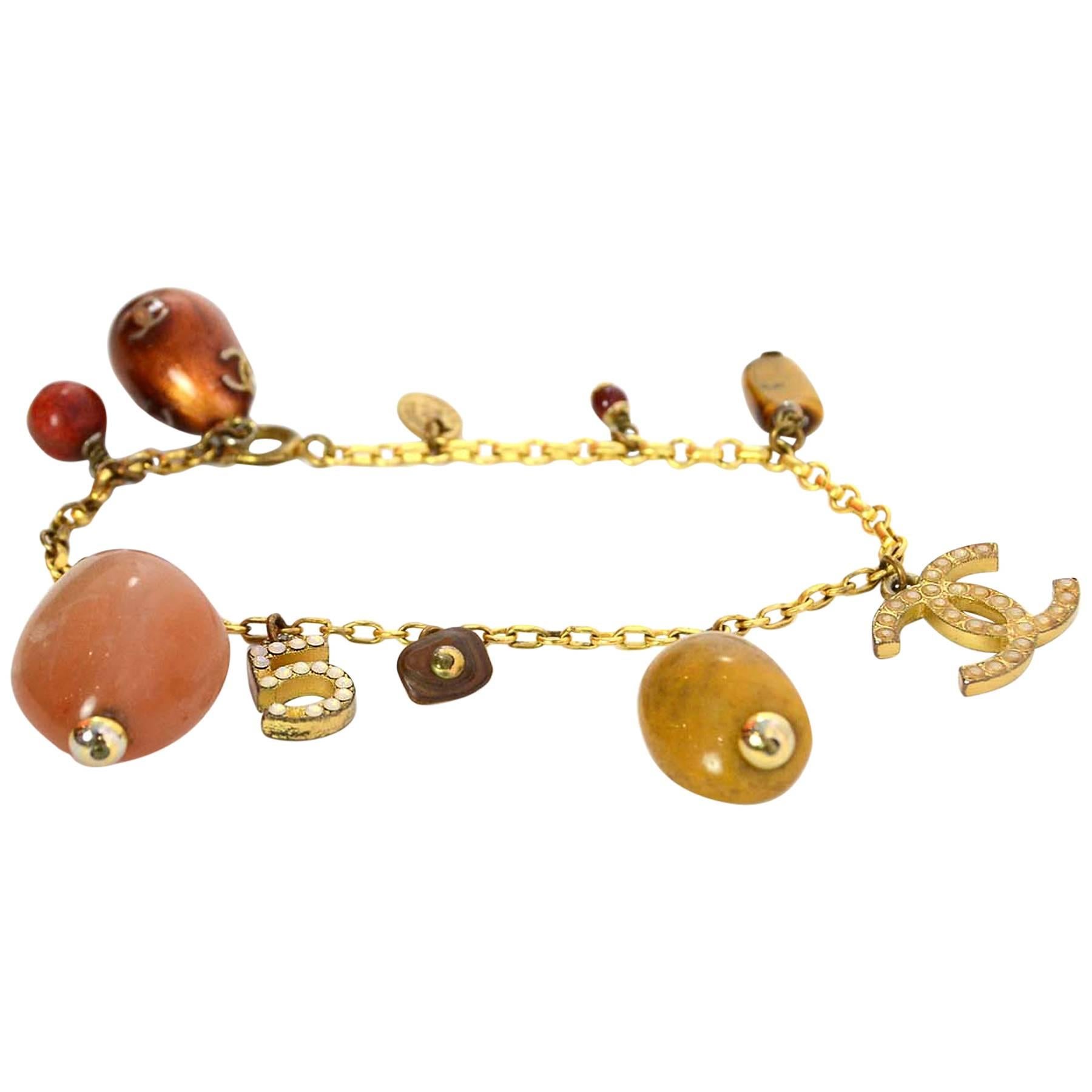 Chanel Gold Chain & Amber Stone Bracelet
Features CC & no 5 charms with crystals

Made in: France
Year of Production: 2001
Stamp: CHANEL 01 CC A MADE IN FRANCE
Closure: Jump ring closure
Color: Gold, amber, bronze
Materials: Metal, stone,