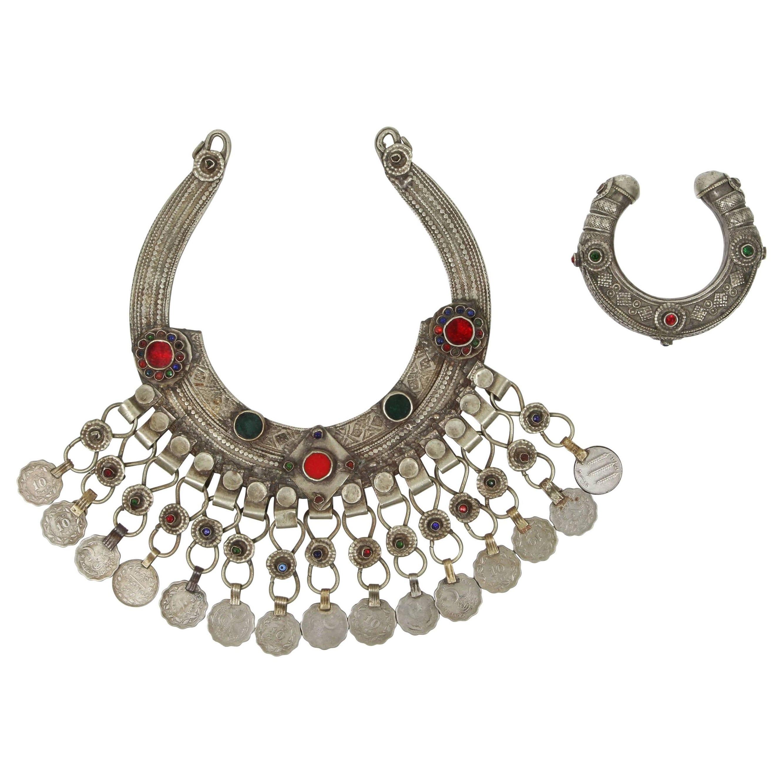 A Moroccan Tribal jewelry vintage bracelet inlaid with colorful glass beads in red and green. Silver, but not of the standard of sterling and richly embellished with applied silver designs and filigree. 
bracelet: 3