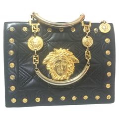 Vintage Gianni Versace black tote bag with golden medusa charms and handles.