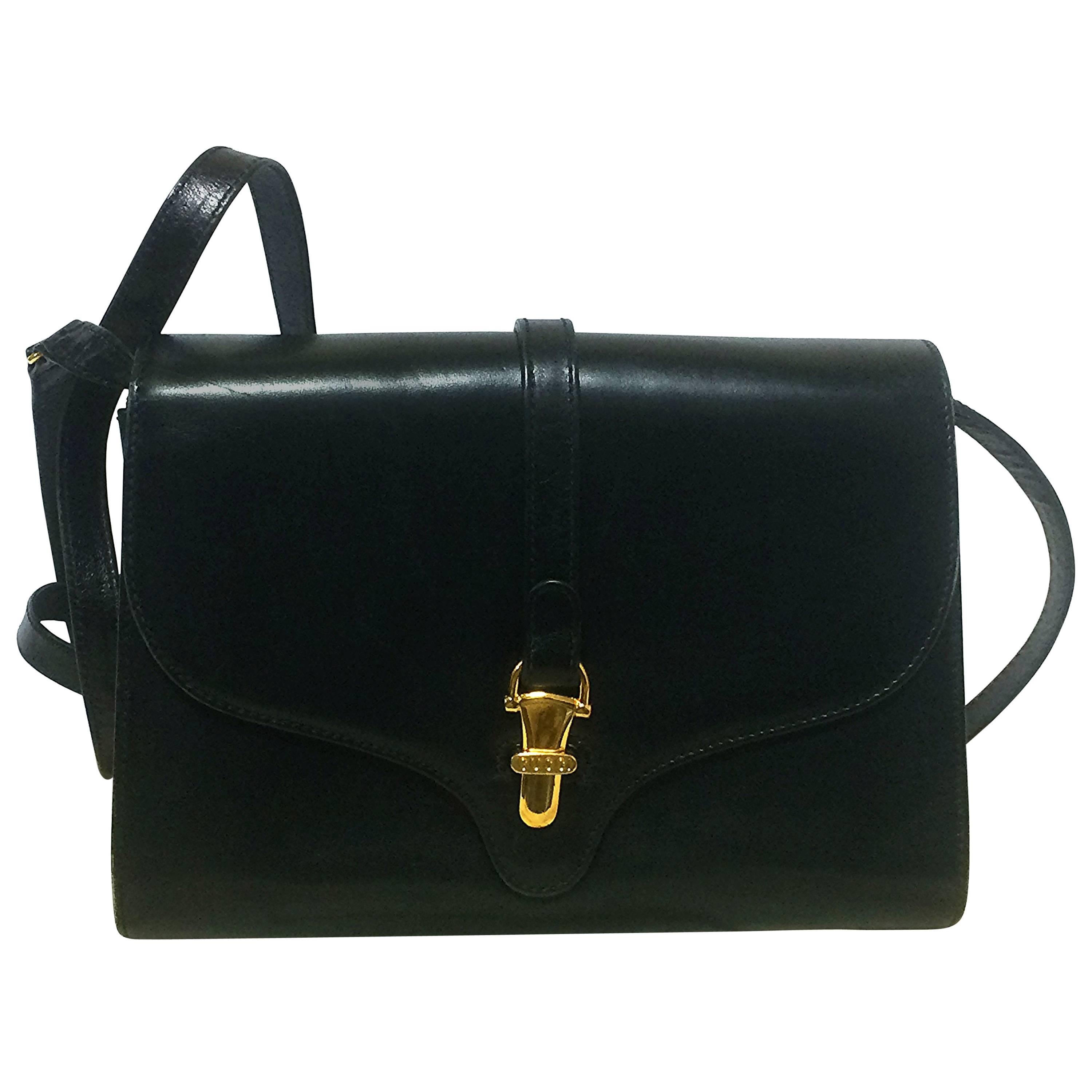 80’s Vintage Gucci black leather clutch shoulder bag with logo motif closure.