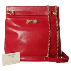 Red shiny leather shoulder bag with gold metal chain and bow Nina Ricci 1980's 