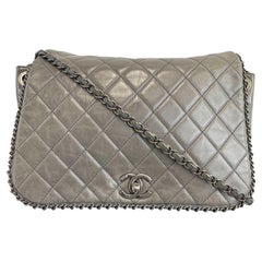 CHANEL - Grand sac à bandoulière en cuir de veau matelassé CC enchâssé gris