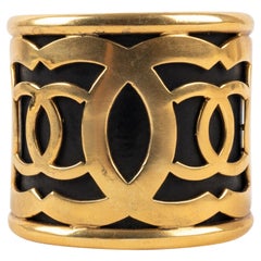 Chanel Manschettenarmband aus goldenem Metall auf schwarzem Hintergrund