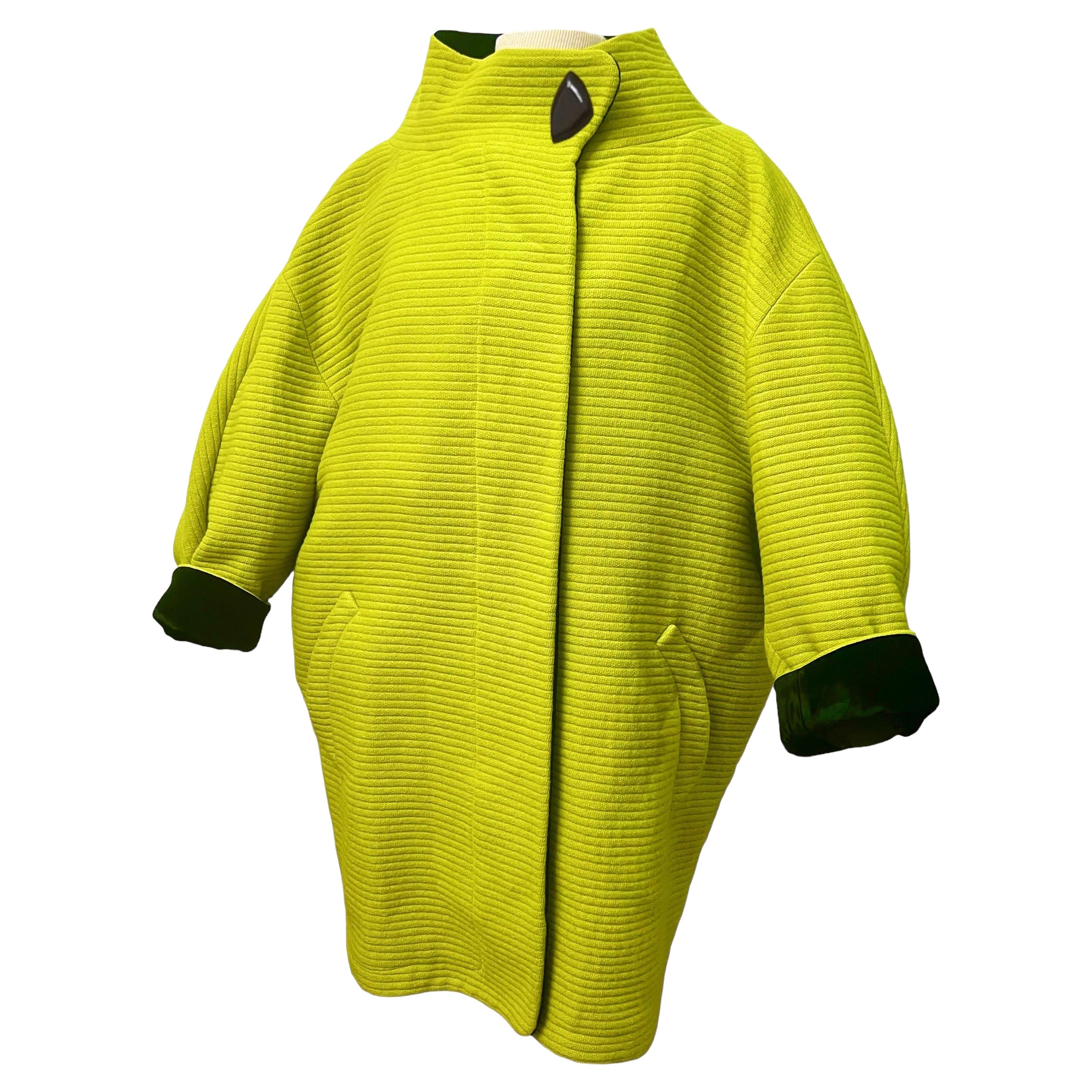 Create a statement with this jaw-dropping avant-garde wool cocoon coat by Thierry Mugler from Fall/Winter 1990. This incredibly rare vivid lime green coat boasts a futuristic design with a wide funnel stand up collar that creates a striking
