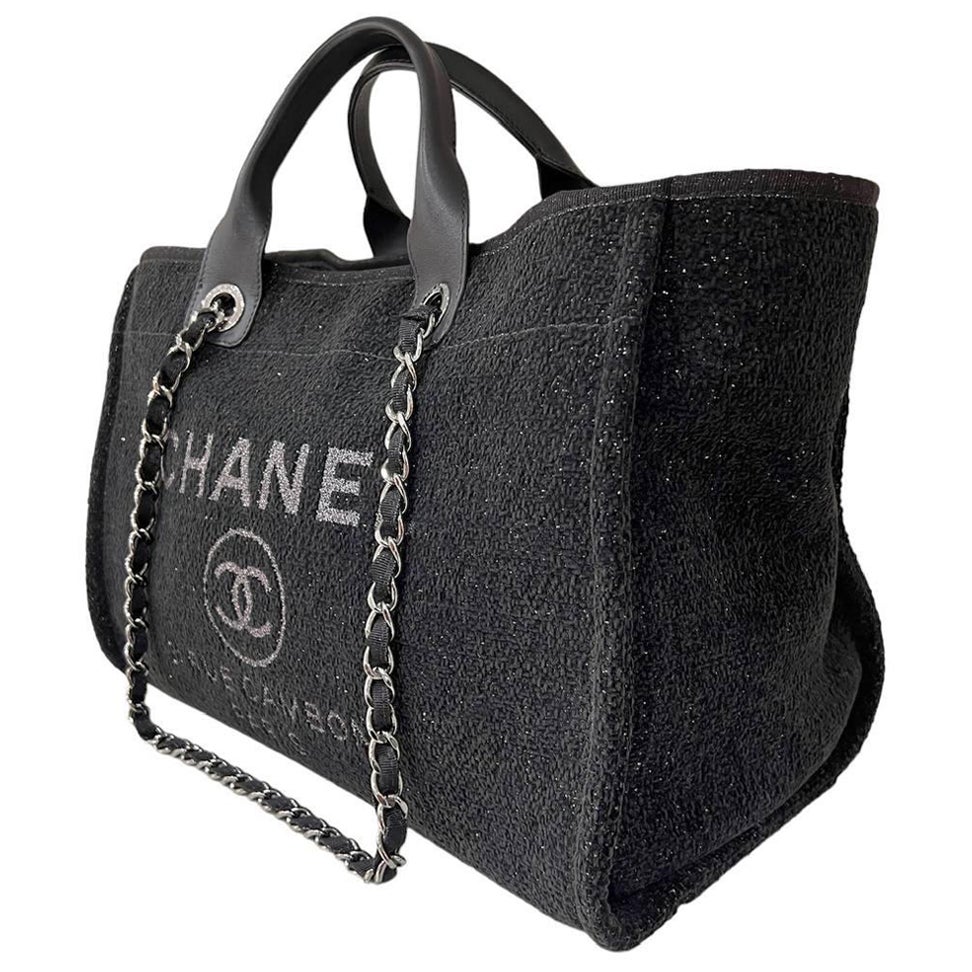 Borsa firmata Chanel, modello Deauville, realizzata in tweed in colorazione nera, con inserti in pelle e hardware argentati. Dotata di una chiusura centrale con bottone calamitato, internamente rivestita in tessuto nero, molto capiente. Munita di