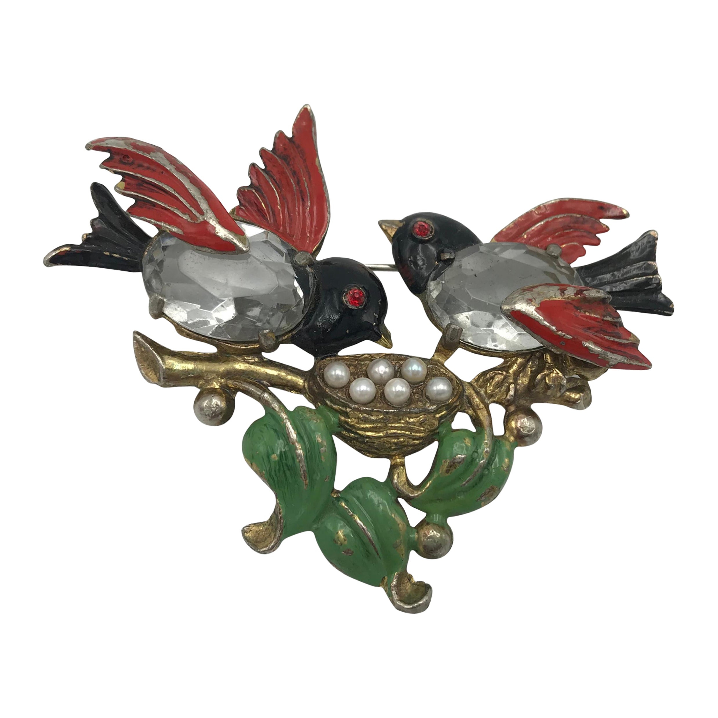A lovable brooch with 2 birds that take care of their treasure together!
The parents of the birds sit on a branch and take care of their eggs. The bodies of the 2 birds are made of 2 polished rhinestones, the wings, head and tails and the leaves are