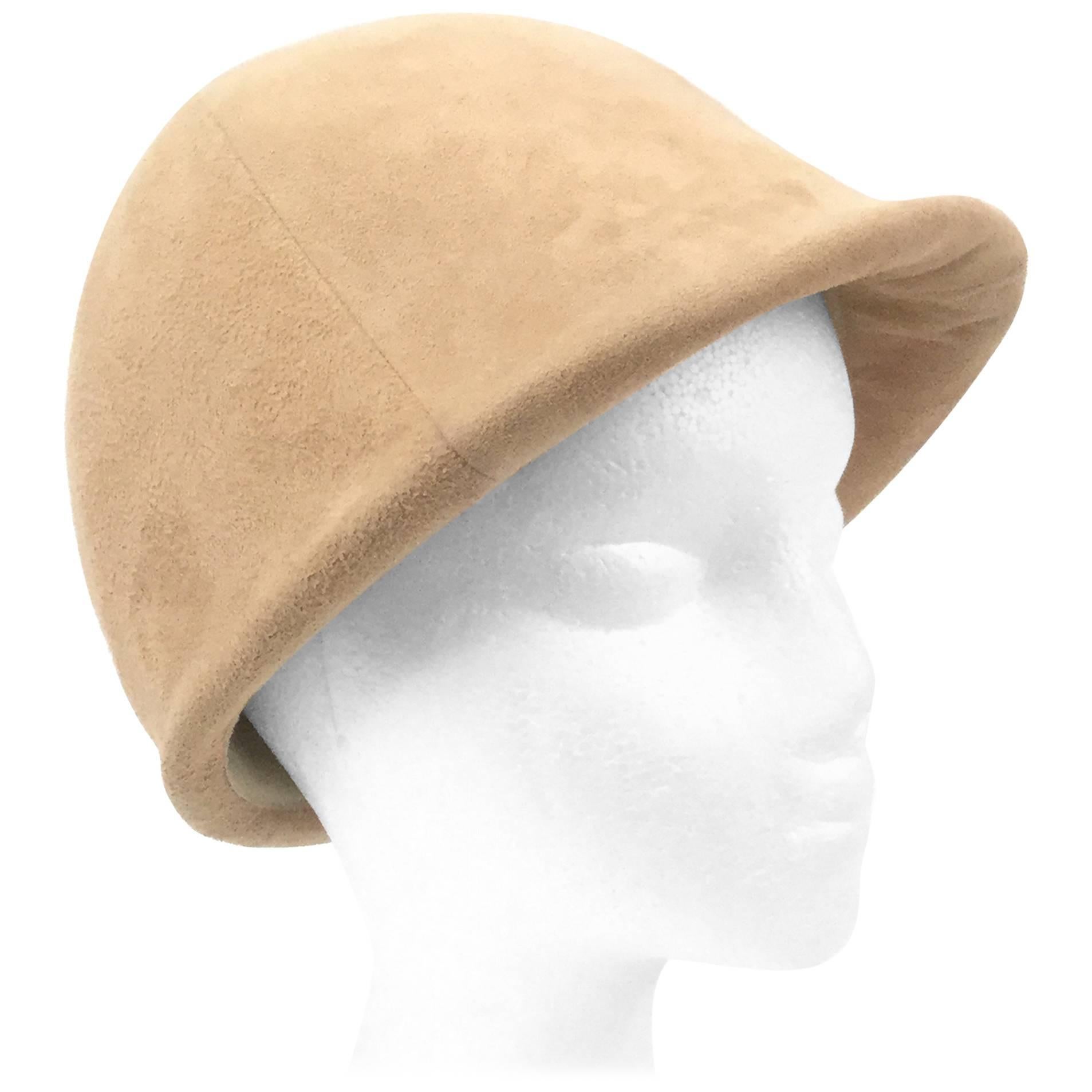Elegant and playful suede mod equestrian hat! This fun hat is composed of four panels of camel colored suede, brought together at the top of the hat's crown and accented with a single plush suede button. The back of the hat has a short decorative