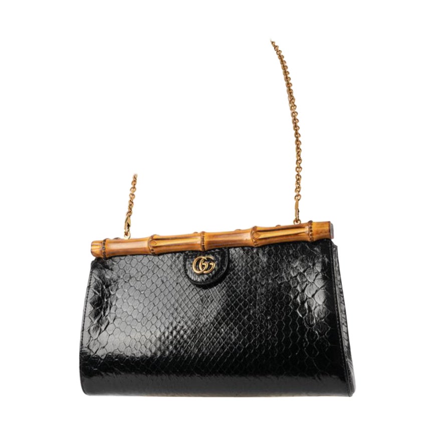 Gucci - Black python clutch with natural bamboo. Golden metal elements and fastener with a magnetic system. The lining is made of tea pink bendable calfskin. The strap is removable and retractable.

Additional information: 
Condition: Very good