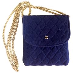 Mini pochette en jersey matelassé bleu marine vintage de Chanel, porte-monnaie et long collier.