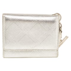 Cartera tríptico Versace con colgante V en piel repujada plateada